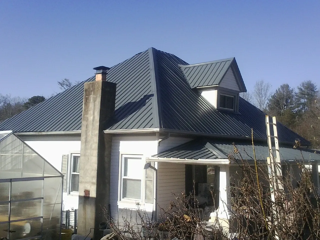 Dark blue standing seam metal roof on a white farmhouse with dormer — Slate & Tile Roof Repair by Roofing Brothers in Micaville