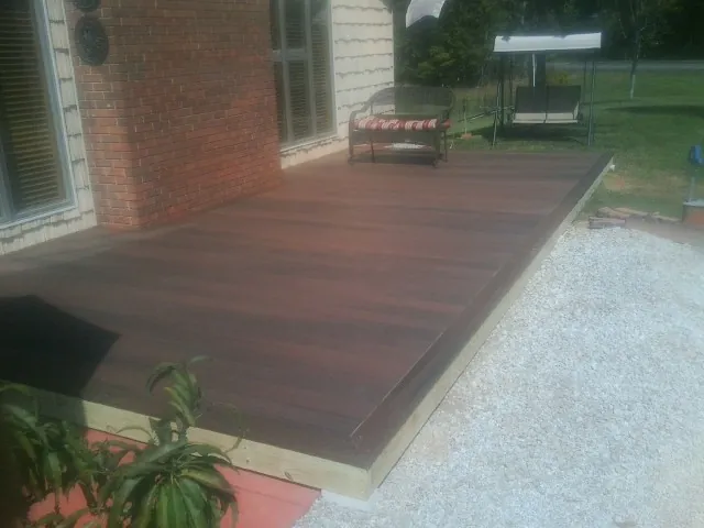 Freshly stained wood deck built against a brick home in Micaville