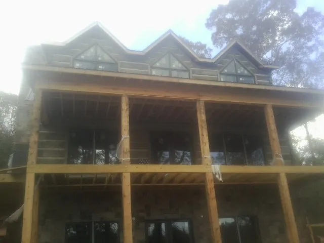 Dormers and porch framing on a large log home under construction — Roof Coating work by our crew in Micaville