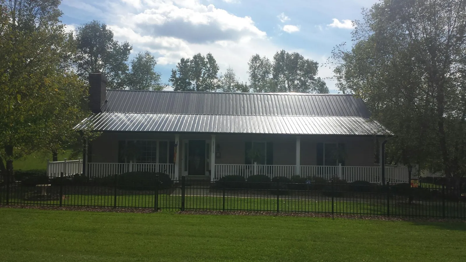 Gray metal roof on a brick ranch with a full width front porch — Gutter Guard Installation work by our crew in Micaville