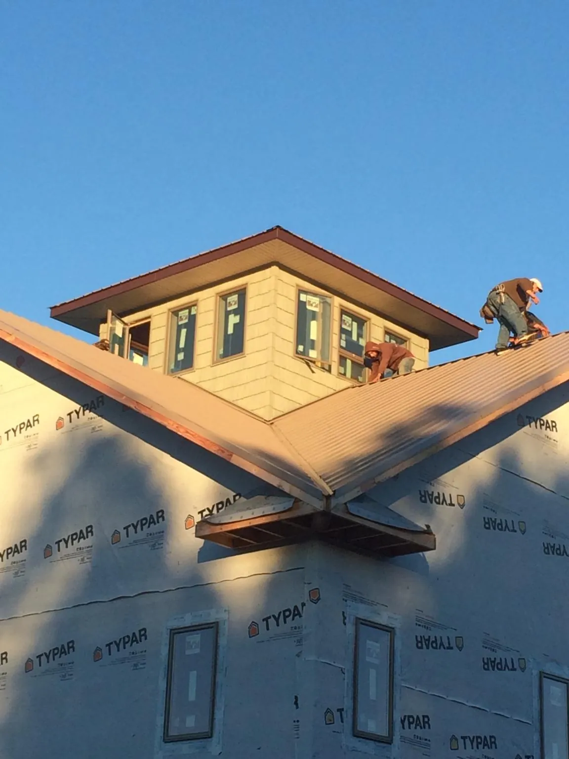 Roofers working around a rooftop cupola on a new metal roof at sunset — Roof Waterproofing in Micaville by Roofing Brothers